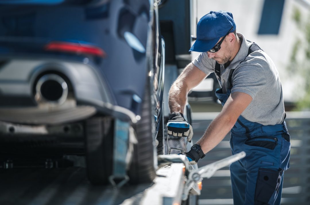 towing-company-worker-securing-vehicle-on-the-truck-platform.jpg